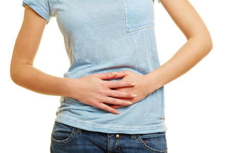 Young woman with bellyache holding hands on her stomachの写真素材