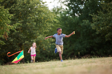Girl and boy flying a kite in summerの写真素材