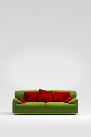 Green sofa with red pillows in front of a white wallの写真素材