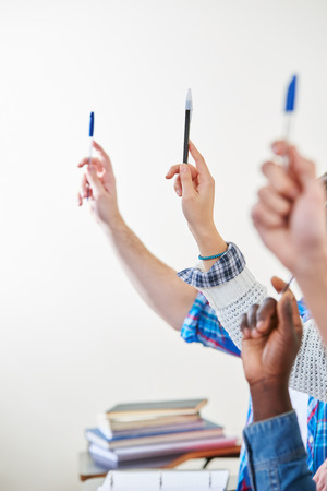 Students with pens in their hands participate in classの写真素材