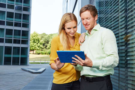 Two young business people using internet connection with a tablet computer