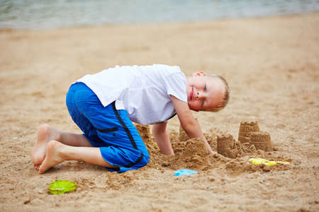 Boy building sand castle in summer on a beachの写真素材