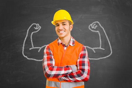 Self-confident construction worker in front of chalkboard with muscles drawn with chalkの写真素材