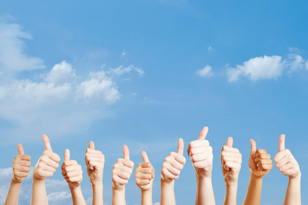 Many hands over the sky with thumbs up as motivationの写真素材