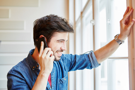 Young man calling with smartphone and thinking