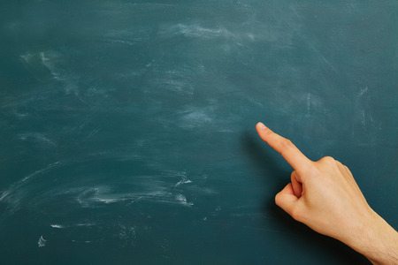 Hand of a teacher pointing to green empty chalkboardの写真素材