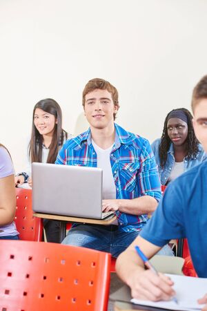 Student taking notes with laptop in class in universityの写真素材