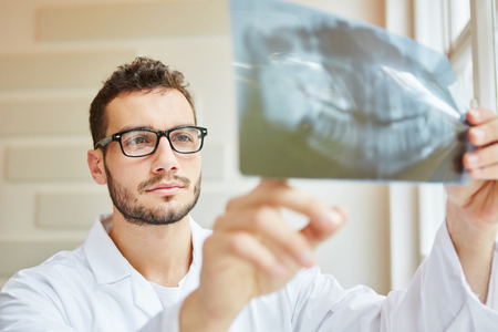 Dentist looking at x-ray image with competenceの写真素材