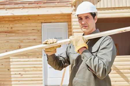 Worker carrying wood at construction site during building construction