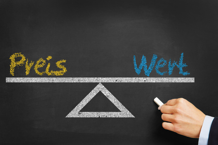 Balance between the German words "Preis" (price) and "Wert" (value) on a chalkboardの写真素材