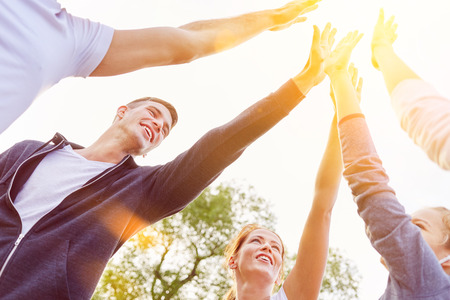 Team of teenagers High Five in the air in summer as friendship and success concept