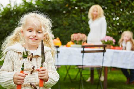 Blond girl with knife and fork at garden in autumnの写真素材