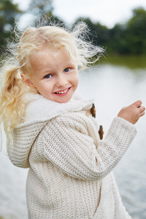 Blond little girl with curls in the nature in autumnの写真素材