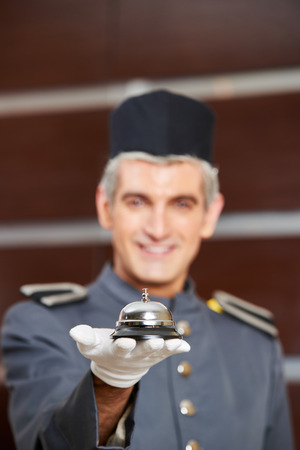 Hotel bell on hand of concierge as service symbolの写真素材
