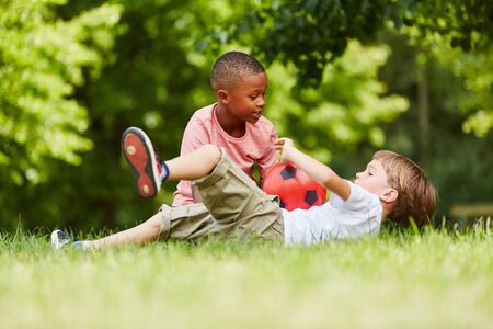 Two boys playing soccer together in the park in summer