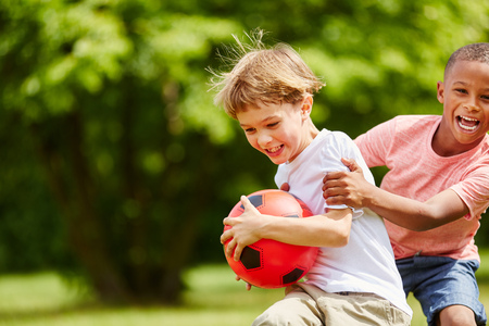 Two children having fun in summer playing with soccer ball as friendsの写真素材