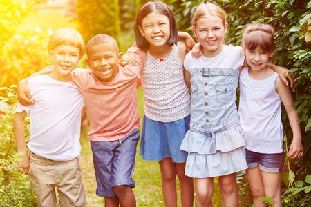 Group of children smiling as friends together in summer in gardenの写真素材