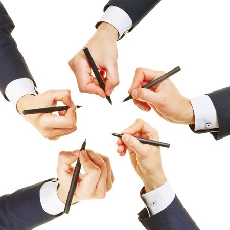 Many hands of business men with pens writing in a circleの写真素材