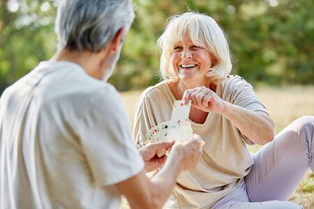 Happy senior couple playing cards in the garden in summerの写真素材