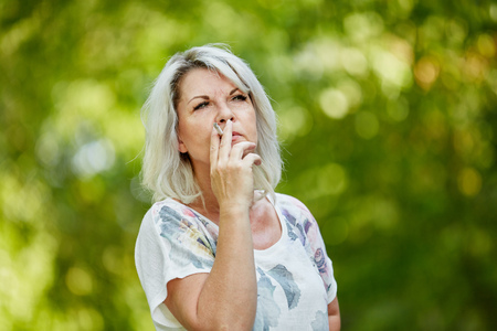 Senior woman smoking a cigarette for relaxing in summerの写真素材