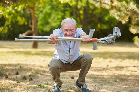 Old man with vitality and crutches in rehab having funの写真素材
