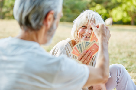 Seniors playing cards together in the garden in summerの写真素材