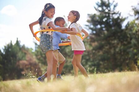 Interracial group of children playing with dance hoop at the parkの写真素材