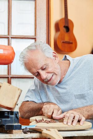 Craftsman as guitar maker works with care and precision on new guitarの写真素材