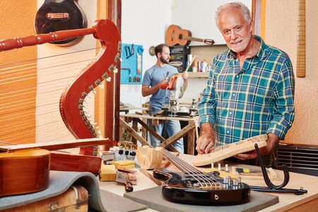 Senior citizen as luthier makes new guitar at his shopの写真素材
