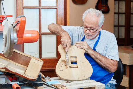 Senior guitar maker makes new guitar with care at luthier's wood workshop