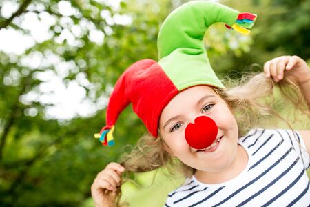 Cheerful girl as clown having fun at childrens birthday partyの写真素材