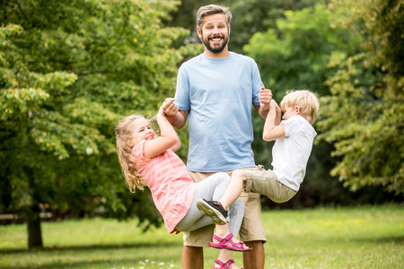 Children and father play as a family in the park having funの写真素材