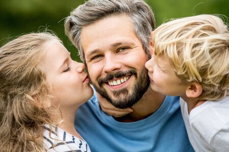 Children kissing father with love as a happy familyの写真素材