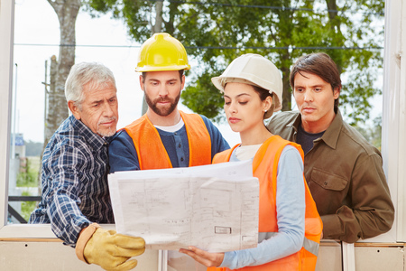Building construction team planning new house with floorplan