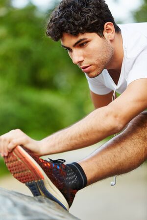 Man stretching feet before running at the park