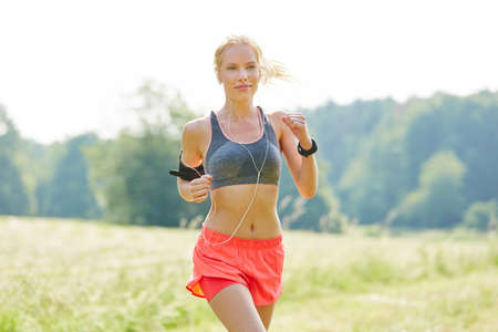 Young woman as jogger with mp3 player listens to music while runningの写真素材