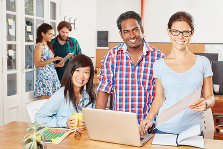 Interracial team of startup students with laptop in coworking business officeの写真素材