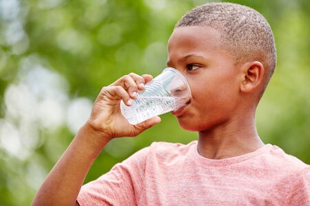 Thristy african boy drinks water from plastic cup