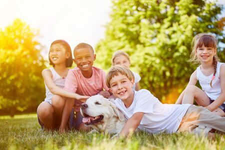 Happy group of kids with Golder Retriever in the parkの写真素材