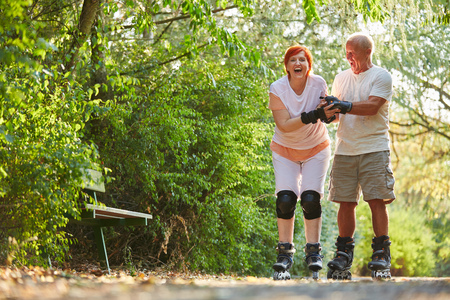 Senior couple having fun while skating in the parkの写真素材