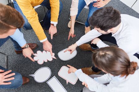 Business team in circle at team building workshop speech bubbles exercise