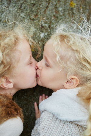 Kiss between two little sisters as sign of sibling love and kids affectionの写真素材