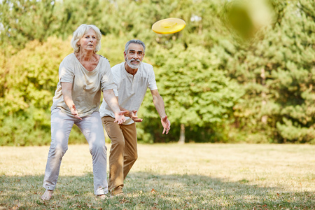 Active senior couple playing with flying disc with vitality in summerの写真素材