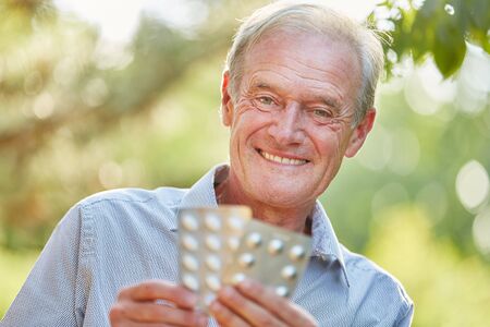 Senior man with medicament in his hands laughing in summerの写真素材
