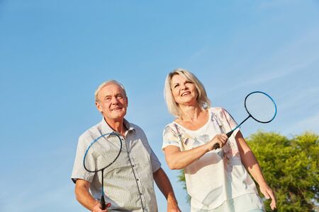 Happy senior citizens playing badminton as a team in summerの写真素材