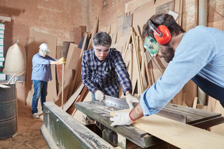 Cooperation and work cutting wood at carpenty workshop