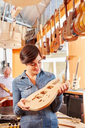 Woman as luthier making new guitar at carpenter's shopの写真素材