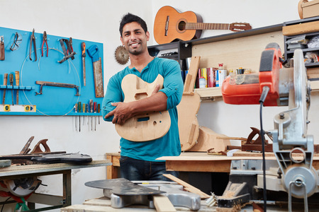 Craftsman shows handmade guitar body at his workshopの写真素材