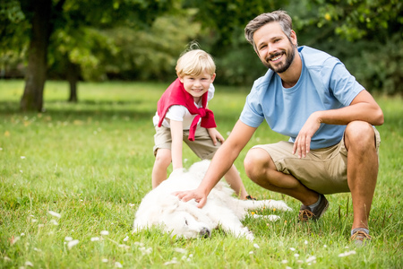 Boy and father as family with dog playing together in summer