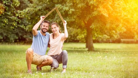 Couple with insurance and building construction concept hold roof over their headsの写真素材